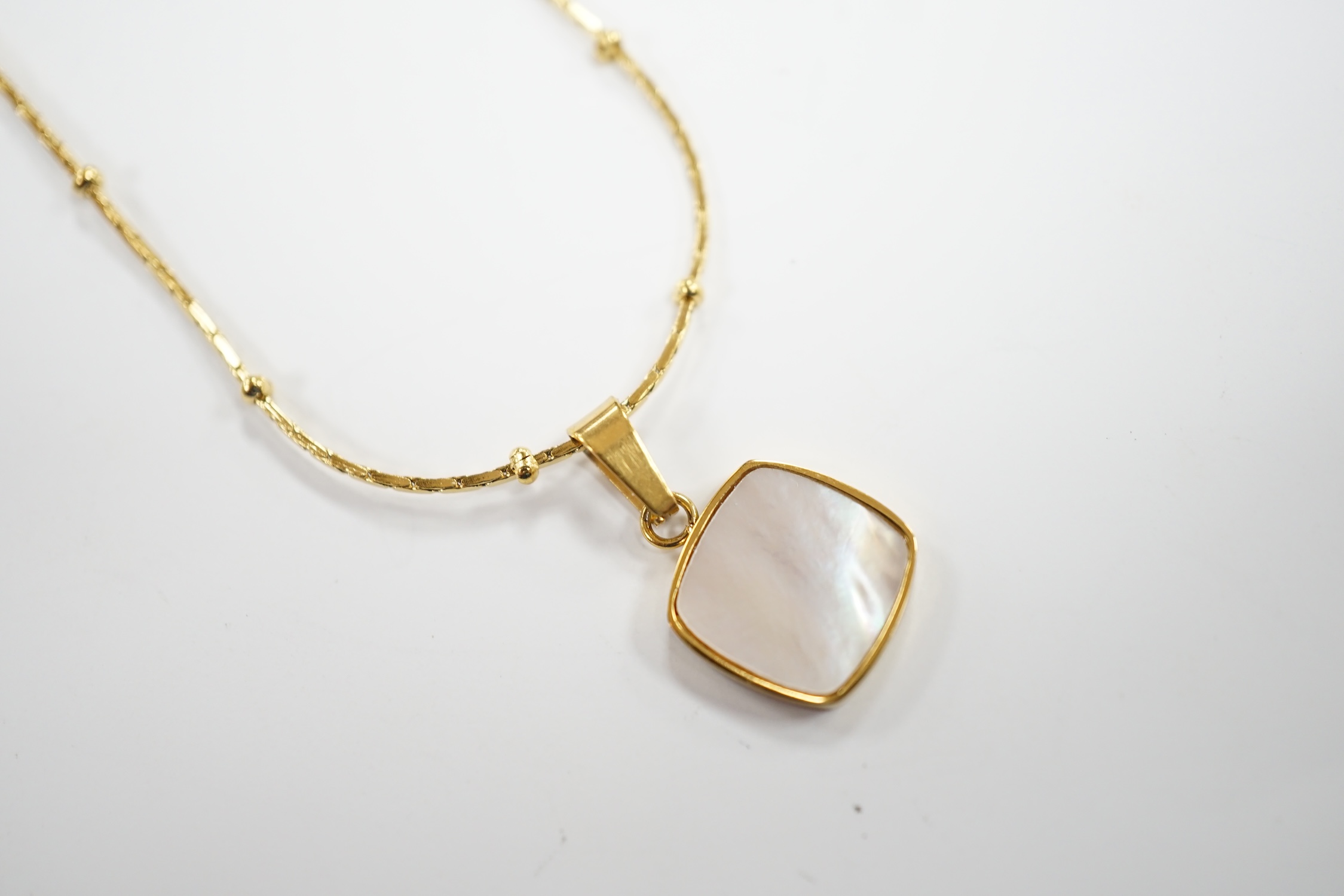 A yellow metal and mother of pearl inset pendant, 11mm on a 18kt fine link chain, 42cm, gross weight 3.4 grams.